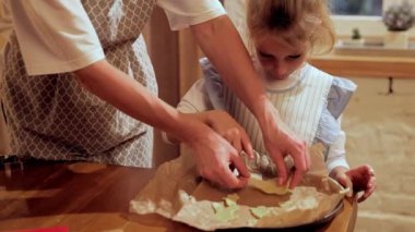 Anne ve küçük kızı evde yemek pişiriyor, Noel kurabiyeleri pişiriyor. Evde sıcak bir akşam. Fırın tavasına hamur koymak. Kurabiye günü kavramı, annelik, çocukluk, tatiller, aile