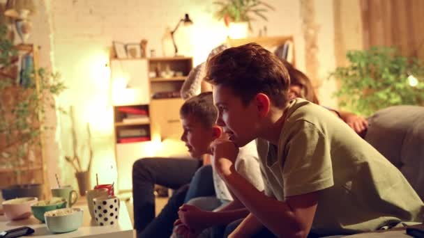 情绪激动的男人 女人和孩子坐在沙发上 父母和孩子一起看电视 足球赛翻译 赢了比赛 闲暇时间 童年和为人父母的概念 — 图库视频影像