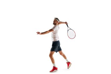 Spor giyimli genç bir adam, tenis oyuncusu, beyaz arka planda izole edilmiş raketle topa vuruyor. Spor anlayışı, hobi, aktif ve sağlıklı yaşam tarzı, rekabet