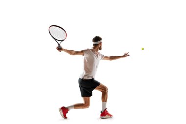 Konsantre genç bir adam, oyun sırasında hareket eden tenis mükellefleri, antrenman, beyaz arka planda izole edilmiş raketle topa vurmak. Spor anlayışı, hobi, aktif ve sağlıklı yaşam tarzı, rekabet