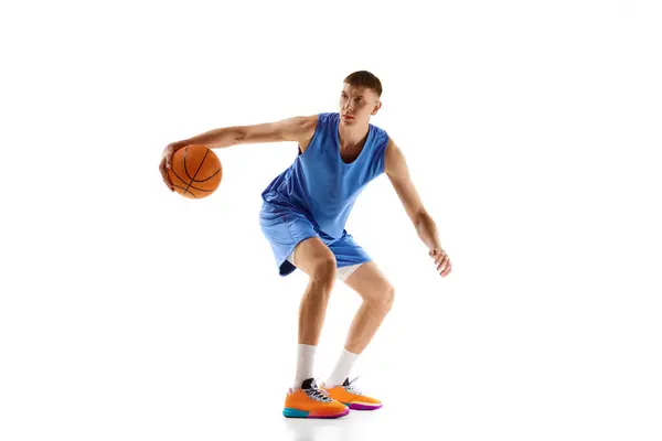 青い制服を着た熱心な若者 運動中のバスケットボール選手 白い背景の上に隔離されたボールで遊ぶ プロスポーツ チャンピオンシップ アクションコンセプト アドベンチャー — ストック写真