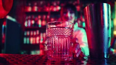 Kokteyl bardağına odaklan. Barda, gece kulübünde çalışan, tatlı ve ekşi kokteyl yapan, bardağa buz koyan genç bir kız. Gece hayatı kavramı, bar, parti, alkol içeceği, mixolog