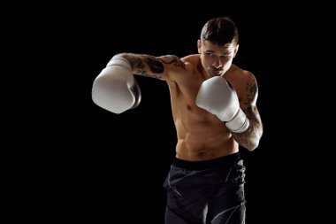 Kanca. Kaslı, üstsüz genç bir adam, boksör eğitimi, siyah arka plan için izole edilmiş bir dövüş. Profesyonel spor anlayışı, dövüş sporu, dövüş sanatları, güç