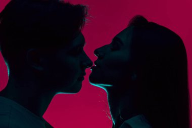 Yumuşak burun öpücüğü. Genç adam ve kadın, şefkatli çift öpüşüyor, mor arka planda, neon ışıkta sarılıyorlar. Romantizm, aşk, ilişki, tutku, gençlik, flört, mutluluk kavramı