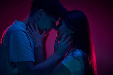 Romantik, sevgi dolu, şefkatli genç bir kadın ve erkek. Mor arka planda öpüşen bir çift. Romantizm, aşk, ilişki, tutku, gençlik, flört, mutluluk kavramı