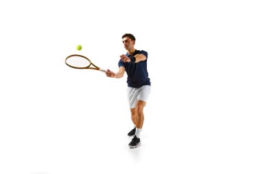 30 'larında rekabetçi bir adam, hareket halinde bir tenisçi, raketle topa vuruyor, beyaz arka planda tek başına antrenman yapıyor. Profesyonel spor, rekabet, oyun, matematik, hobi, eylem kavramı