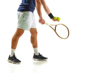 Mavi tişörtlü ve beyaz şortlu erkek tenisçinin beyaz arka planda izole edilmiş raketle servis yapan görüntüsü. Profesyonel spor, rekabet, oyun, matematik, hobi, eylem kavramı