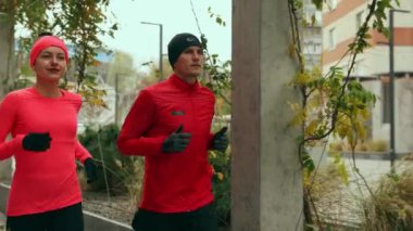Genç bir adam ve bir kadın, kırmızı spor giyim giyen arkadaşlar sabah koşusu için dışarıda buluşuyorlar. Sonbahar sabahında antrenman. Spor anlayışı, aktif ve sağlıklı yaşam tarzı, rekabet, dinamik, maraton