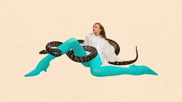 Contemporary art collage. Weird woman in white blouse and blue tights sitting with snake in her legs against peach color background. Concept of feminine strength and power, wisdom, mystical aura.