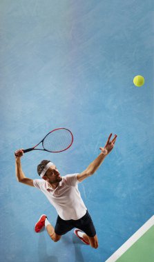 Genç bir adamın en iyi görüntüsü, hareket halindeki bir tenisçi, raketle topa vuruyor, tenis kortunda oynuyor, antrenman yapıyor. Spor, rekabet, turnuva, eylem, başarı kavramı