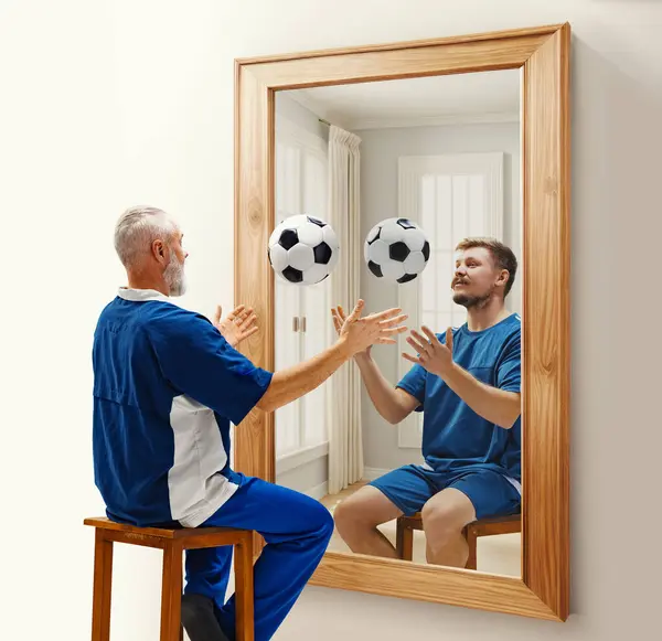 Senior man in uniform sitting with football ball near mirror with reflection of his younger self. Conceptual collage. Concept of present, past and future, age, life cycle, generation, ad