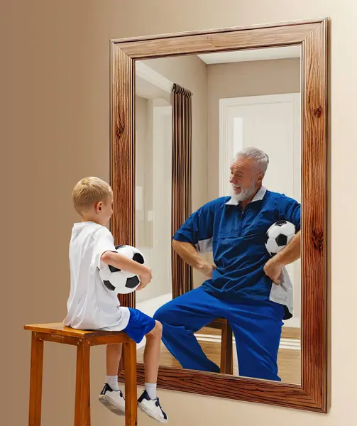 Little boy, child with football ball sitting and looking in mirror with reflection of senior man, Kid in future. Conceptual collage. Concept of present, past and future, age, life cycle, generation
