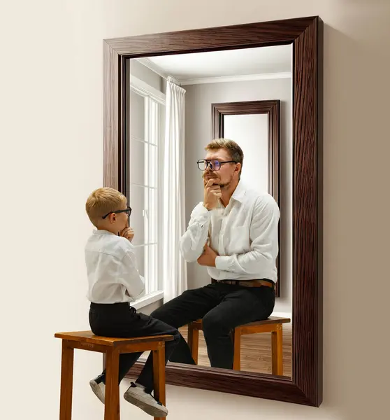 Little boy, child sitting near mirror and imagining him being adult man. Thinking abut future. Conceptual collage. Concept of present, past and future, age, life cycle, generation, ad