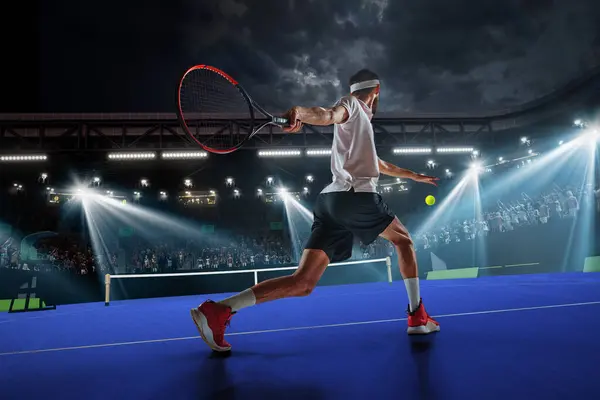 Dynamic image of young man, tennis player in motion during game, hitting ball with racket. Tennis court and fan zone. Concept of sport, competition, tournament, action, success