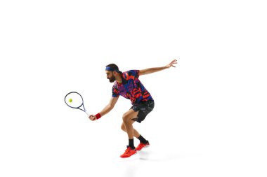 Yoğunlaşmış bir adam, oyun sırasında hareket eden bir tenis oyuncusu, beyaz arka planda izole edilmiş raketle antrenman yapıyor, topa vuruyor. Profesyonel spor, hareket, rekabet, eylem kavramı. Ad