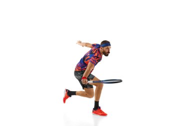 Yoğunlaşmış bir adam, oyun sırasında hareket eden bir tenis oyuncusu, beyaz arka planda izole edilmiş raketle antrenman yapıyor, topa vuruyor. Profesyonel spor, hareket, rekabet, eylem kavramı. Ad