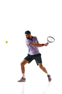 Konsantre rekabetçi genç adam, oyun sırasında hareket eden tenis oyuncusu, beyaz arka planda soyutlanmış olarak oynuyor. Profesyonel spor, hareket, rekabet, eylem kavramı. Ad