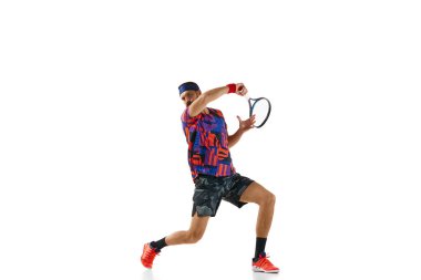 Renkli üniformalı sakallı genç adam yağmur yağıyor, beyaz stüdyo arka planında izole edilmiş raketle tenis topu oynuyor. Profesyonel spor, hareket, rekabet, eylem kavramı. Ad