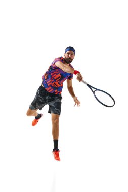 Renkli üniformalı sakallı genç adam yağmur yağıyor, beyaz stüdyo arka planında izole edilmiş raketle tenis topu oynuyor. Profesyonel spor, hareket, rekabet, eylem kavramı. Ad