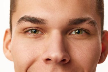 Beyaz stüdyo arka planına karşı erkek yüzü, gözleri, burnu ve kaşları yakın plan kesilmiş. Erkek güzelliği, cilt bakımı, kaplıca, kozmetoloji, erkek sağlığı kavramı