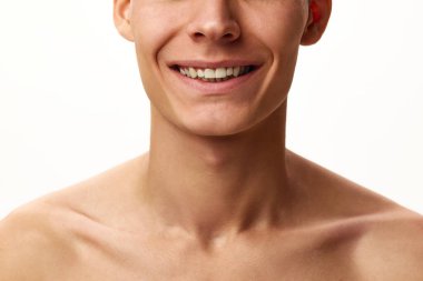 Beyaz stüdyo arka planında erkek yüzü, üstsüz bir beden. Erkek model gülümsüyor. Erkek güzelliği, cilt bakımı, kaplıca, kozmetoloji, erkek sağlığı kavramı