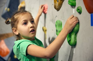 L: Küçük kız, kaya atma kursuna giden çocuk, eğitim, kapalı alandaki duvara tırmanma. Spor eğitimi. Kayalık, spor tırmanışı, hobi ve aktif yaşam tarzı, okul, eğitim kursu kavramı