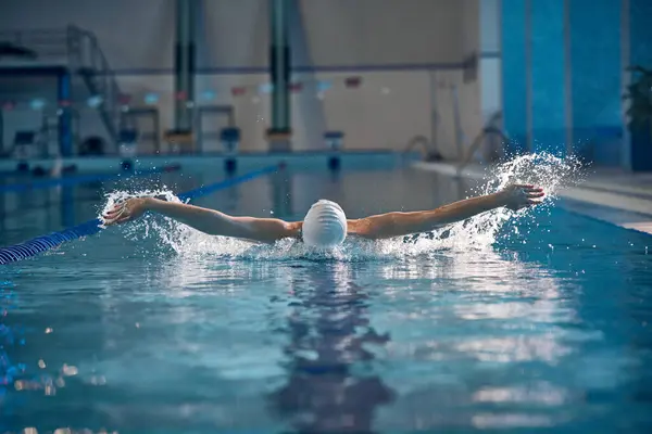Butterfly swimming techniques. Athlete, woman in motion, training, swimming in pool, wearing cap and goggles. Concept of pool sports, water sport, competition, active lifestyle