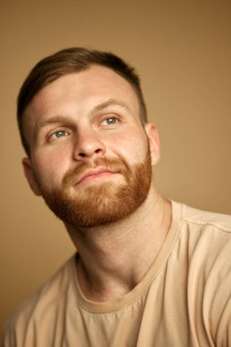 Kızıl saçlı ve ayılı çekici bir adamın bej renkli stüdyo arka planına bakan portresi. Güzellik, kişisel bakım, hijyen, kozmetik, kaplıca kavramı. Ad