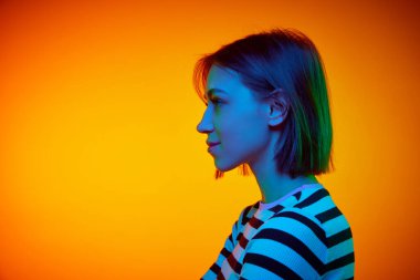 Kısa saçlı çekici bir kızın profil portresi gradyan turuncu arkaplan ve metin eklemek için negatif alan. Güzellik, gençlik, sanat, insan duyguları, yüz ifadesi kavramı.