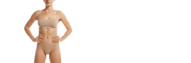 Kaslı, zayıf ve rahatlamış bir kadın vücudu. Beyaz stüdyo arka planında iç çamaşırlarıyla poz veren bir model. Pankart. Doğal güzellik, sağlık ve vücut bakımı, kilo kaybı, spa, ilaç kavramı