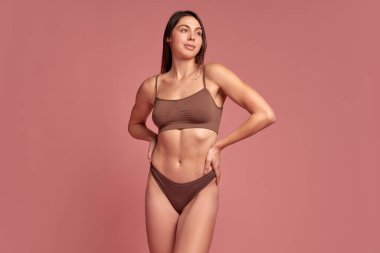 İç çamaşırı reklamı. Pembe arka planda pamuklu iç çamaşırı giyen güzel bir genç kız. İnce vücutlu bir model. Doğal güzellik kavramı, vücut bakımı. Marka promosyonları, katalog kapakları