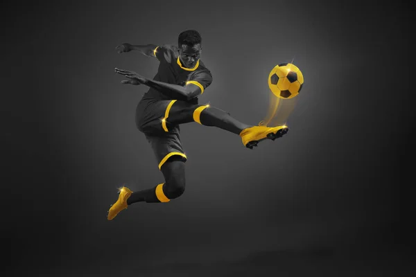 Sports Event Promotion. Young African man, soccer player in motion kicking ball. Black and yellow elements. Focus and movement. Perfect for advertising international soccer events, like the World Cup