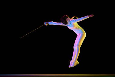 Güç ve zarafet. Eskrim sanatında güç ve zarafet kombinasyonu gereklidir. Kadın sporcu, eskrimci neon ışıkta siyah arka planda hareket halinde. Spor anlayışı, rekabet, hobi