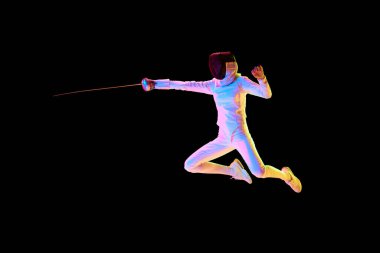 Tam teçhizatlı bir eskrimci, hassas bir şekilde saldırıyor, neondaki siyah arka planda izole edilmiş. Hareket halindeki kadın sporcu, kılıç eğitimi alıyor. Profesyonel spor, rekabet, şampiyonluk, başarı konsepti