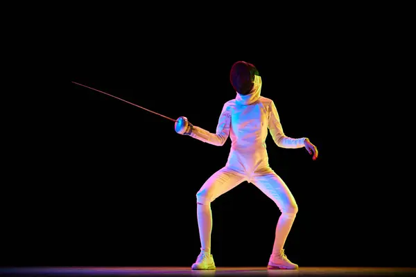 Martial arts and discipline. Fencing, martial art requiring discipline and strategy, perfect for related themes. Female athlete training over black background in neon. Concept of sport, competition