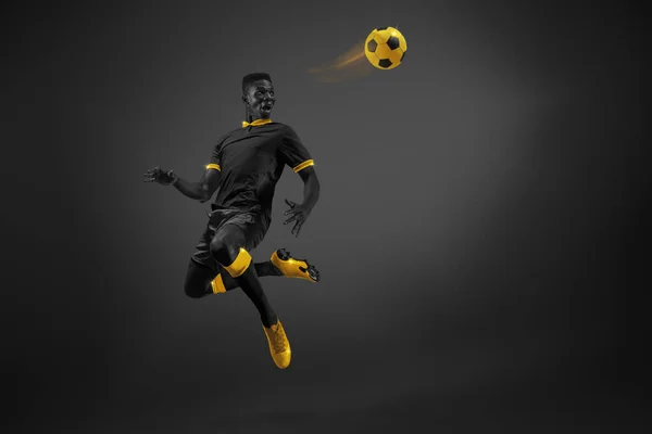Black and yellow color combination. Young African man, football player in motion kicking ball with leg in air. Tournament. Poster for sport events, competition and championship. Energy boost