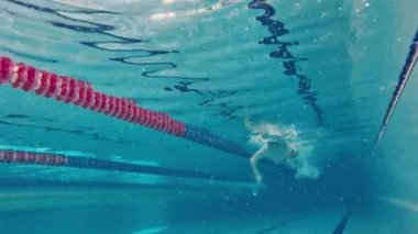 Profesyonel atlet. Genç bir adam, yüzme sporcusu, havuzda yüzen kep ve gözlük takıyor. Havuz sporları, su sporları, rekabet, aktif yaşam tarzı kavramı