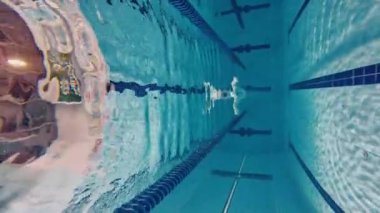 Su altında yüzmek. Mayolu genç bir adam antrenman yapıyor, havuzda yüzüyor. Hız ve dayanıklılık. Havuz sporları, su sporları, rekabet, aktif yaşam tarzı kavramı