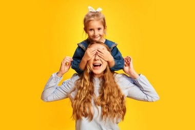 - Sürpriz. Küçük kız, kızının sarı stüdyo geçmişine karşı annesinin gözlerini kapatması. Kadınlar bayramını kutluyoruz. Anneler Günü kavramı, Uluslararası Mutluluk Günü, aile, annelik.