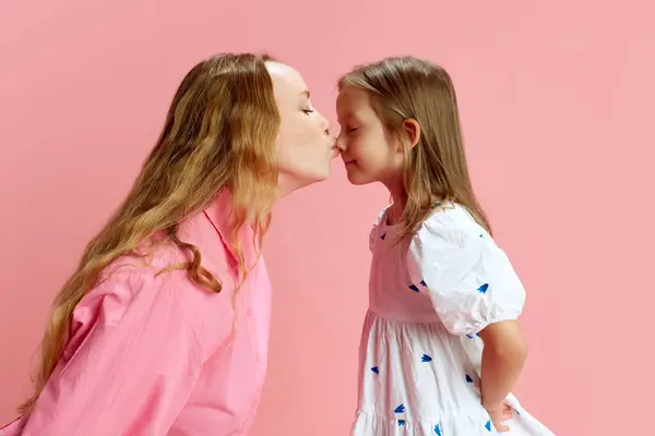 珍惜母性 有爱心的母亲在粉红的工作室背景下亲吻她的小女儿们的鼻子 支持和爱 母亲节 国际幸福日 亲子关系的概念 — 图库照片