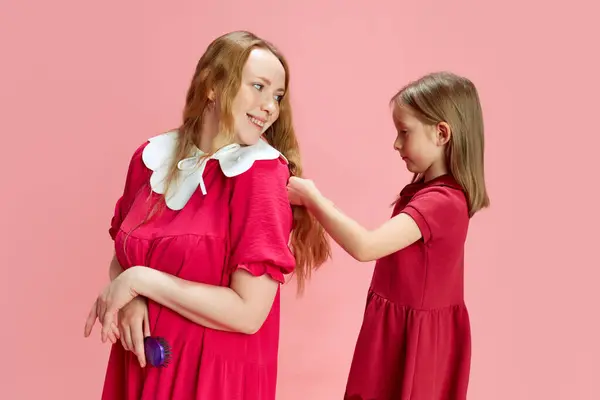 有其父必有其女 小女孩在粉红的工作室背景下给她妈妈做发型 家人的目光 母亲节 国际幸福日 关心和爱的概念 — 图库照片