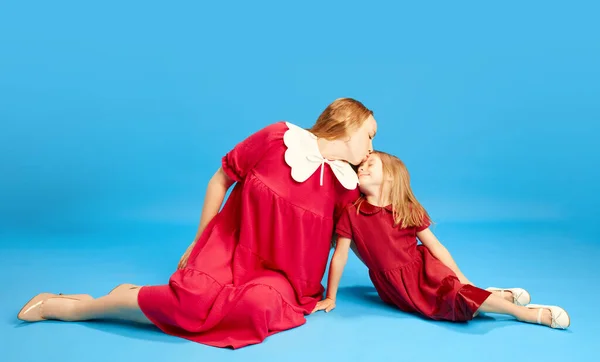 愛情あふれる母親は 小さな娘に愛情を示し 青いスタジオの背景に対して額にキスをしました 母の日 国際幸福の日 子供時代の概念 — ストック写真