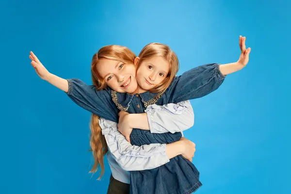 愛とケアで成長する幸せな少女 笑顔の母親が娘を抱きしめている ブルースタジオの背景 母の日のコンセプト 国際幸福デー 子供時代 子供の日 — ストック写真