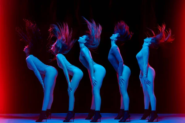 Impressive performance. Young women in bodysuits dancing on high heels against black background in neon light. Concept of modern dance style, creativity and beauty, art, hobby
