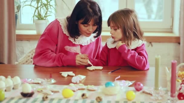 美しく 愛情あふれる若い女性 小さな娘とジンジャーブレッドを飾る母親 休日の準備 ベーキング 休日のコンセプト イースター 母性と子供時代 — ストック動画