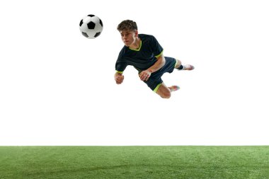 Genç bir adamın dinamik görüntüsü, hareket halindeki bir futbolcu, kafasıyla topa vuruyor beyaz arka planda çimen döşemesi ile izole edilmiş. Spor, oyun, rekabet, şampiyonluk, aktif yaşam tarzı kavramı