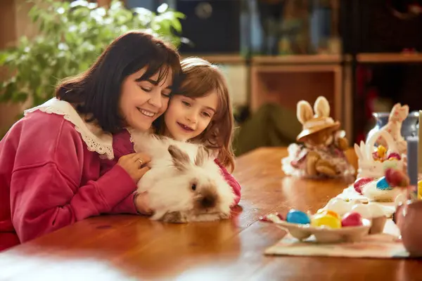 Playful positive time. Mother spending time with her little daughter, playing with bunny. Family celebrating Easter. Concept of holiday, Easter, family, motherhood and childhood