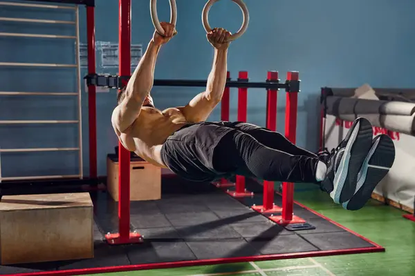 Hard training, String young man, with shirtless, muscular, relief body doing Frontlever exercise on gymnastic rings in gym. Concept of active and healthy lifestyle, body care, fitness, sport