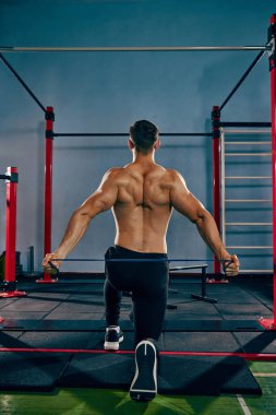 Antrenman. Sportif, sportif genç adam spor salonunda üstsüz antrenman yapıyor direnç bandıyla egzersiz yapıyor, genişliyor. Aktif ve sağlıklı yaşam tarzı kavramı, vücut bakımı, fitness, spor