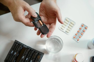 Hap kutusu tutan yaşlı bir adamın elleri. Haftanın günleriyle etiketlenmiş ilaç kutuları. Günlük haplar ve vitaminler için organizatör. Sağlık ve tıbbi bakım, yaşlanma, ilaç, tedavi kavramı